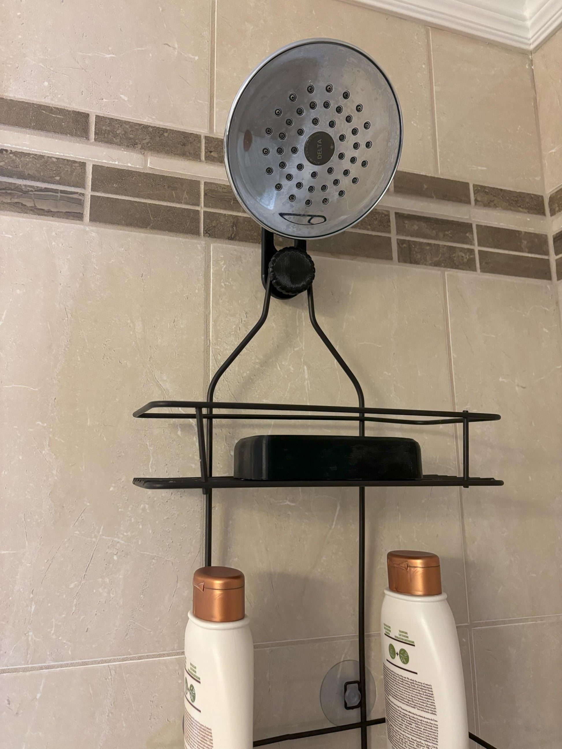 Standard-hook black shower caddy extension hanger mounted on angled shower arm in tiled bathroom.
