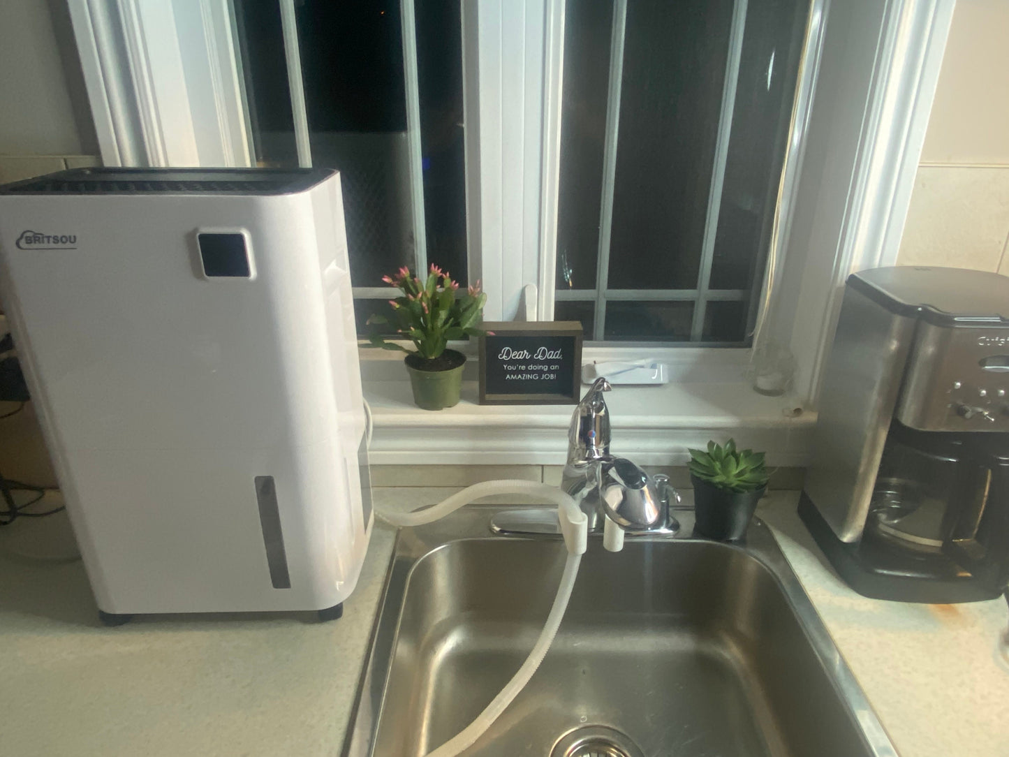 Portable Dehumidifier setup with drain hose bracket clipped onto kitchen sink faucet for easy drainage