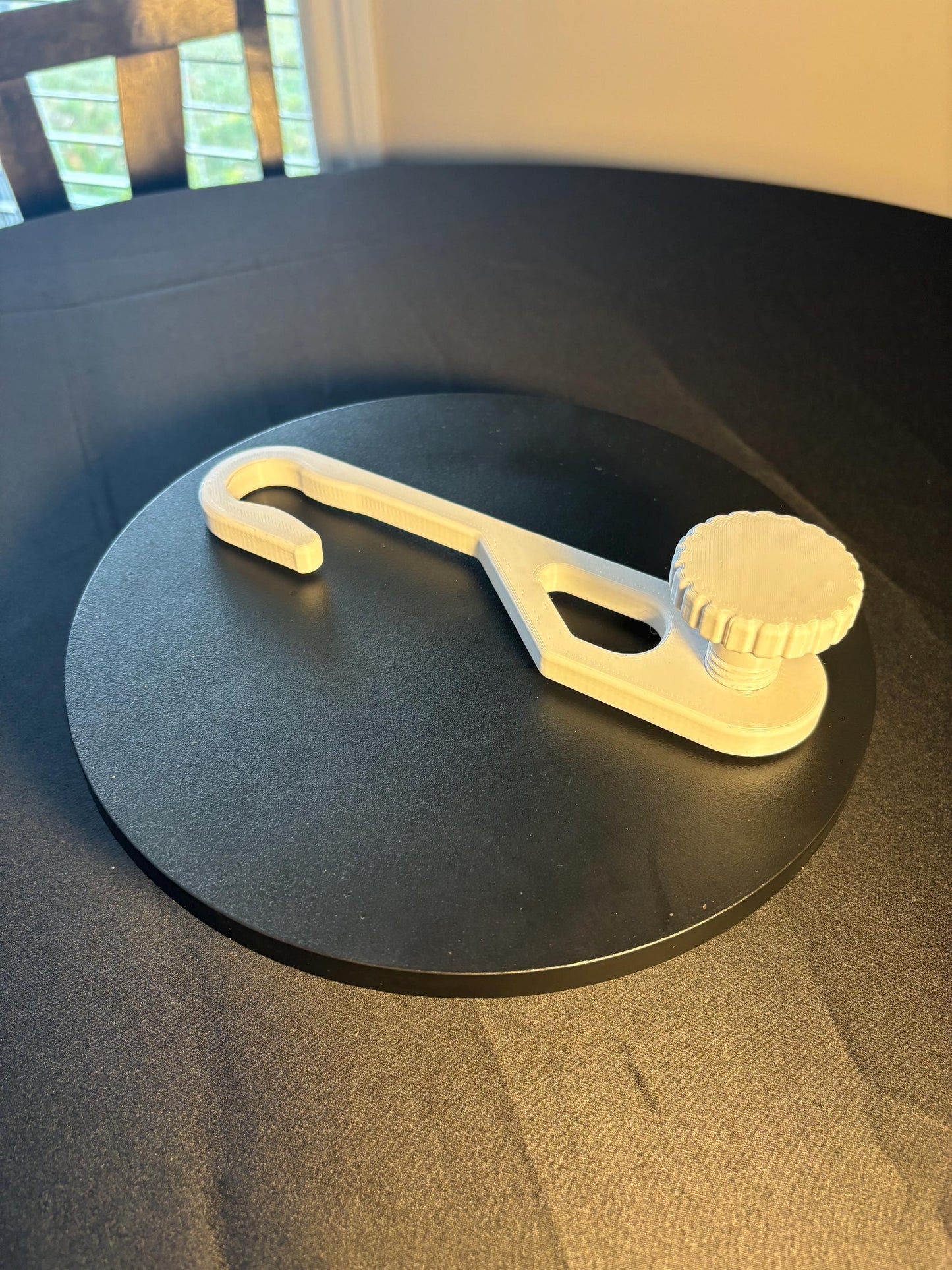 Standard-hook white shower caddy extension hanger with adjustment knob in studio lighting on black background Angle view.