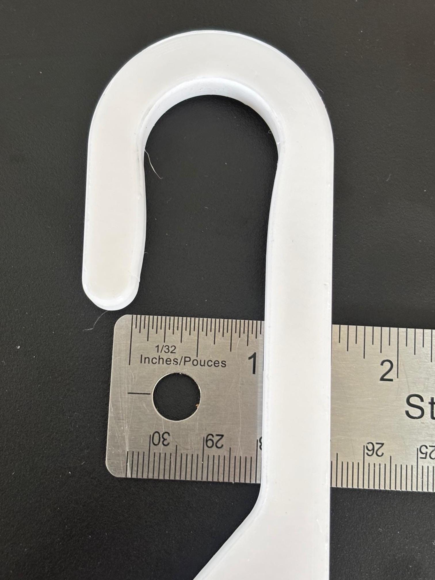 Close-up measurement of wide-hook white shower caddy extension hanger showing approximately 1-inch hook opening